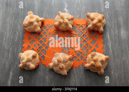 Papel-picado-Tischdecke auf Holztablett als mexikanische Tag-der-Toten-Dekoration mit köstlichem, fluffigem und zuckerhaltigem Brot der Toten Stockfoto