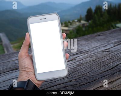 Handy mit leerem weißem Bildschirm als Platzhalter. Frauenhand, die beim Schreiben mit dem Mobiltelefon auf dem Schreibtisch in den Ferien hält. Arbeitspersonal für Kontakte, Marketing, Geschäft und Technologie Stockfoto