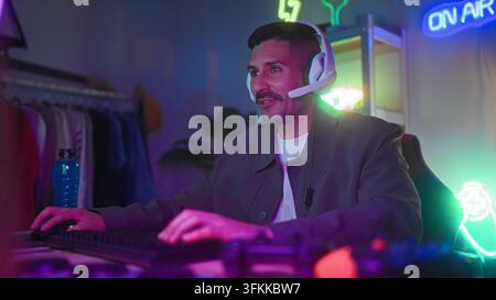 Mann mit Headset, Hände auf Tastatur und Maus, spielt am Computer im Streaming-Studio; konzentrierte Online-Session. Stockfoto