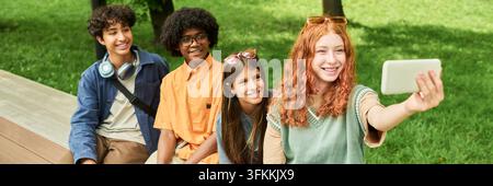 Verschiedene Gruppe von lächelnden Teenagern, die im Freien ein Selfie mit dem Smartphone machen Stockfoto