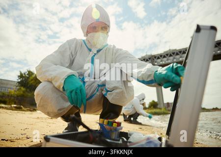 Porträt eines Wissenschaftlers in Schutzanzug, der Wasserproben nimmt Stockfoto