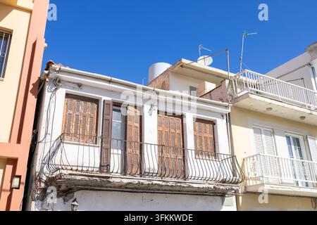 Traditionelle griechische Wohnhäuser in Zakynthos, Griechenland, mit verwitterten Holzläden, Balkonen, Dachantennen, Wassertank und farbenfrohen Nachbarn Stockfoto