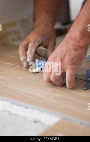 Arbeiterhände, die während der Renovierung Fliesen auf dem Boden verlegen Stockfoto