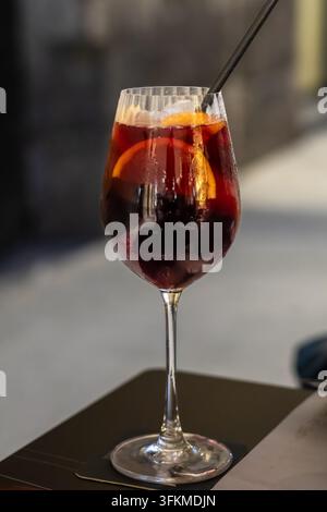Traditionelle spanische Sangria, serviert in einem Weinglas mit Eis, Orangenscheiben und Strohhalm auf einem Cafétisch Stockfoto