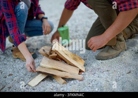Nahaufnahme eines Paares, das auf einem sandigen Strand ein Lagerfeuer baut, während eines Herbst-Campingausflugs Stockfoto
