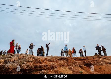 Nazare, Portugal - 6. Dezember 2025: Menschen stehen auf Klippen und beobachten den Ozean und die großen Wellen bei Sonnenuntergang in Nazare, Portugal Stockfoto