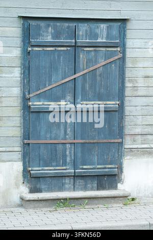 Vintage-verwitterte blaue Holztüren an einer rustikalen Holzfassade Stockfoto
