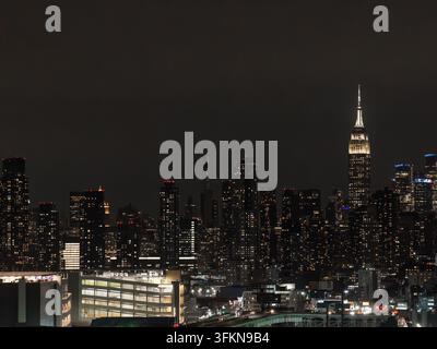 Eine Luftaufnahme zeigt die beleuchtete Stadtlandschaft von Manhattan bei Nacht in New York, wobei bekannte Wolkenkratzer wie das Empire State Building wieder leuchten Stockfoto