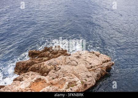 Türnisches Mittelmeerwasser spritzt sanft auf ein Küstenfelsen Stockfoto