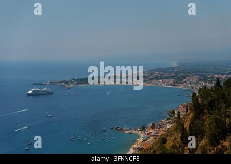 Panoramablick auf die Bucht von Giardini Naxos in Sizilien mit einem großen Kreuzfahrtschiff, sommerliche mediterrane Küstenlandschaft, Reiseziel, Taormina Stockfoto