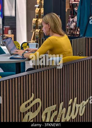 Prag, Tschechische Republik – 25. September 2026: Frau arbeitet an einem Laptop im Tchibo-Café in einem Einkaufszentrum Stockfoto