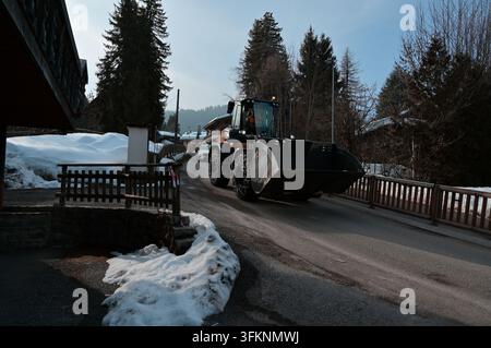Ein mit Schneeketten ausgerüsteter Radlader rumpelt über ein verschneites Megève Stockfoto