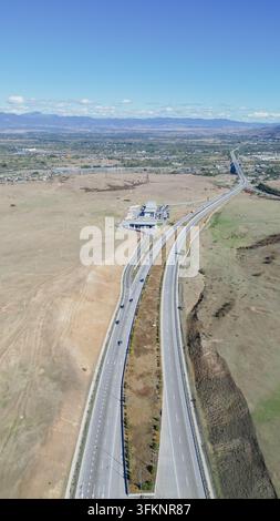Vertikale Luftaufnahme einer modernen mehrspurigen Autobahn, auf der Autos fahren, die sich durch weite Felder der Region Gori in Shida Kartli erstrecken Stockfoto