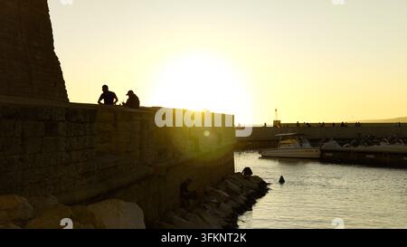 MARSEILLE, FRANKREICH - 16. SEPTEMBER 2026 - Silhouetten von Menschen, die die goldene Stunde am Alten Hafen von Marseille, Frankreich, genießen Stockfoto