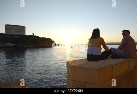 MARSEILLE, FRANKREICH - 16. SEPTEMBER 2026 - Paar beobachtet goldenen Sonnenuntergang über dem Mittelmeer mit dem Pharo-Palast in Marseille, Frankreich Stockfoto