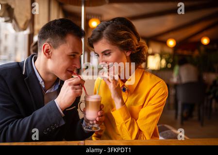Glücklicher junger Mann füttert eine Frau mit einem Löffel ein Dessert Stockfoto