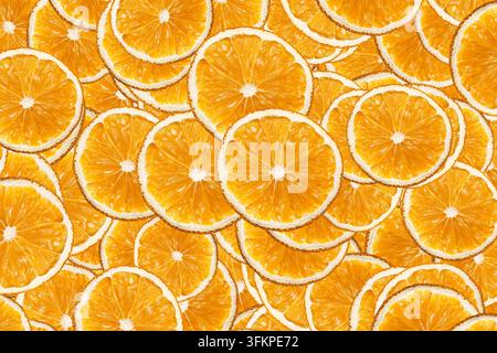 Getrocknete Orangenscheiben, die als farbenfrohes Muster angeordnet sind. Zitrusfrucht-Hintergrund für getrocknete Lebensmitteltextur-Dekoration natürliche Zutaten und gesunde Snacks. Stockfoto