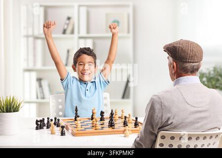Enkel schlägt Opa beim Schach, isoliert auf weißem Hintergrund Stockfoto