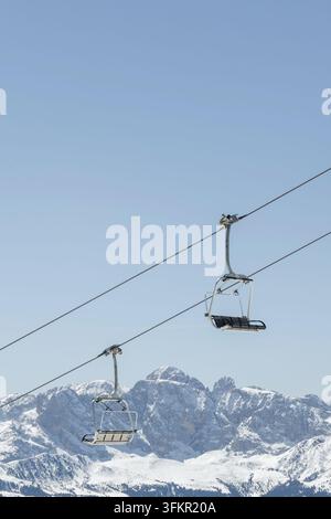 Skilifte bewegen sich über eine schneebedeckte Landschaft in den Dolomiten, Italien, während der Winterskisaison. Die Berglandschaft zeigt die italienischen Alpen. Stockfoto