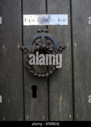 20. September 2026, Loweswater, Vereinigtes Königreich. Ein verwitterter, verzierter Metallklopfer und ein verblasstes Schild mit der Bitte an Besucher: "Bitte schließen Sie die Tür" Stockfoto