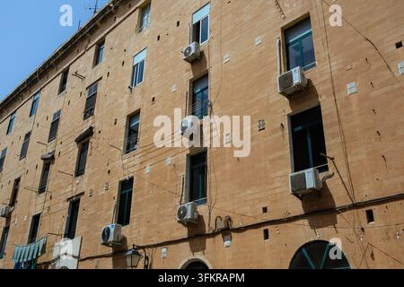 Klimaanlagen-Kondensatoreinheiten, die außerhalb von Fenstern an einem Gebäude in Valletta, Malta, aufgehängt sind Stockfoto