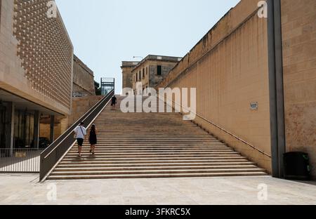 Lange, steile und breite Treppen neben dem Stadttoreingang von Valletta mit Menschen, die zur Straße Papst Pius V hinaufgehen Stockfoto