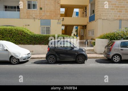 Ein kleiner Smartwagen, der auf einem mittleren Platz mit Autos auf beiden Seiten an der Straße in Malta geparkt ist Stockfoto