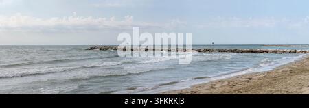 Große Panorama-Landschaft mit Steinmolle an einem sandigen Adriastrand, aufgenommen im sommerlichen Hellen bei Ereaclea Mare, Veneto, Italien Stockfoto