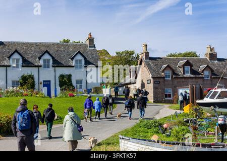 Touristen gehen einen Dorfweg entlang an traditionellen Häusern vorbei, Isle of Iona, Inner Hebrides, Schottland. Stockfoto