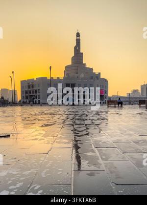 Fanar-Spiralmoschee in Doha, Katar, die sich auf nassem Kopfsteinpflaster während eines weichen, warmen Sonnenuntergangs am Abendhimmel spiegelt. Stockfoto