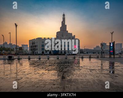 Fanar-Spiralmoschee in Doha, Katar, die sich auf nassem Kopfsteinpflaster während eines weichen, warmen Sonnenuntergangs am Abendhimmel spiegelt. Stockfoto