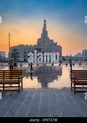 Fanar-Spiralmoschee in Doha, Katar, die sich auf nassem Kopfsteinpflaster während eines weichen, warmen Sonnenuntergangs am Abendhimmel spiegelt. Stockfoto
