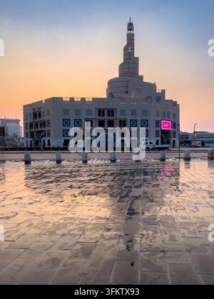 Fanar-Spiralmoschee in Doha, Katar, die sich auf nassem Kopfsteinpflaster während eines weichen, warmen Sonnenuntergangs am Abendhimmel spiegelt. Stockfoto
