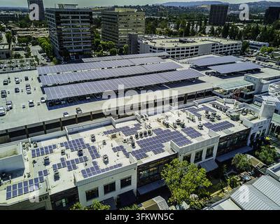 Luftbild der Solarpanel-Infrastruktur auf einem Parkhausdach und einem Gewerbegebäude, mit Photovoltaikzellen und urbaner Architektur in San Stockfoto