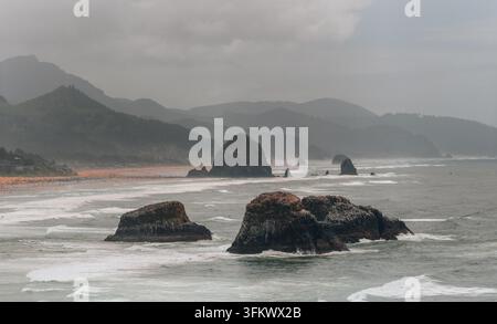 Luftaufnahme von Haystack Rock und der rauen Küste mit brandenden Wellen und nebligen Bergen in Cannon Beach, Oregon, Vereinigte Staaten. Stockfoto