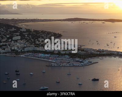 Luftaufnahme des Hafens und der Küste von Cannes bei Sonnenuntergang, mit Yachten, die in der Bucht vor Anker liegen, umgeben von städtischen Gebäuden in Cannes, Provence-Alpes- Stockfoto