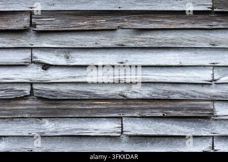 Geradlinige Ansicht von gealtertem horizontalem Holzscheunenverkleidungsbrett, das eine sich wiederholende verwitterte Hintergrundtextur bildet. Stockfoto