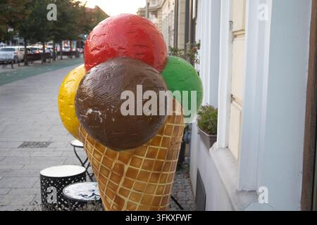 Übergroßes Eisbecher-Display mit bunten Kugeln vor einem Geschäft auf einem Stadtbordstein. Stockfoto