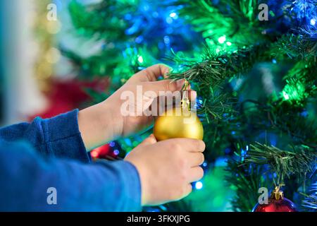 Weihnachten, Ornament und Hände eines Kindes mit Baumschmuck im Urlaub oder Ferien zu Hause. Festlich, Feier und Nahaufnahme mit Glasbauble für Xmas Stockfoto