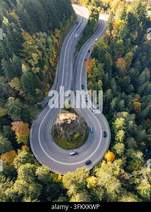Aus der Vogelperspektive einer Haarkurve auf der Bergstraße mit einem Kreuz auf dem Felsen im Herbst Stockfoto