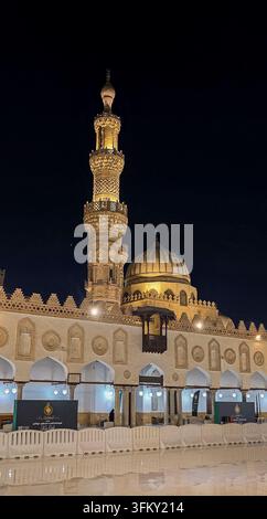 Al-Azhar-Moschee bei Nacht beleuchtet, mit ihrem verzierten Minarett, der Kuppel und dem historischen Hof in Kairo, Ägypten. Stockfoto
