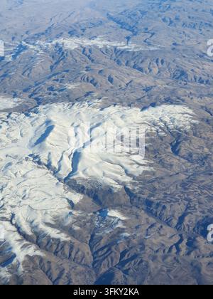Luftaufnahme einer rauen Berglandschaft mit weitläufigen Gletschern und Schneefeldern, die mit felsigem Gelände durchsetzt sind. Das Bild fängt Stockfoto