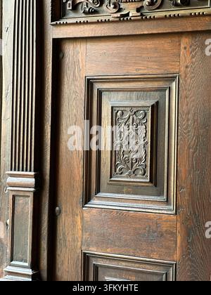 Nahaufnahme eines kunstvoll geschnitzten antiken Holzinnentürfelds. Eine detaillierte Nahaufnahme eines antiken Holztors mit einem kunstvollen geschnitzten Reliefmuster Stockfoto