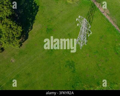 Luftaufnahme direkt über einem Strommast, der in einem grünen Feld in Menston bei Leeds steht und Stromleitungen, Bäume, Zäune, Gras und das Metall zeigt Stockfoto