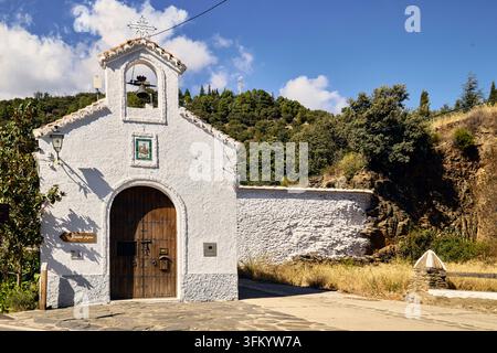 Kapelle in Fuente Agria, Ermita de la Virgin de las Agustias, mit Glockenturm und texturierten Wänden vor dem Hintergrund von üppigen grünen Hügeln und einem Brig Stockfoto