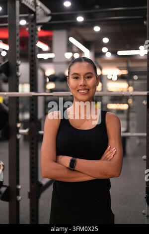 Ein mittelgroßes Porträt einer fröhlichen jungen asiatischen Thai-Isan-Frau, die selbstbewusst mit ihren Armen da steht und direkt in die Kamera lächelt. Erfasst in einem Stockfoto