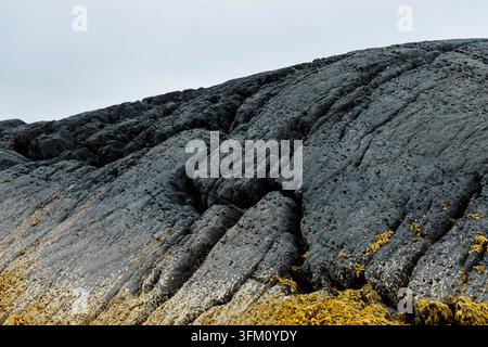 Dunkle vulkanische Basaltsteinstruktur mit Rissen Stockfoto