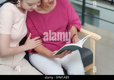 Eine Mutter und ihre Tochter teilen einen ruhigen Moment, während sie gemeinsam ein Buch lesen, was Liebe, Lernen und Verbindung am Muttertag symbolisiert Stockfoto