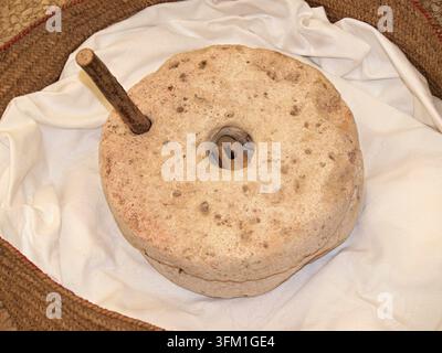 Alte Quernstein mit Holzgriff zum Mahlen von Getreide, der Tradition und Geschichte repräsentiert Stockfoto