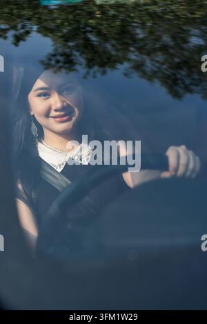 Schöne junge Frau lächelt, während sie ein Auto fährt Stockfoto